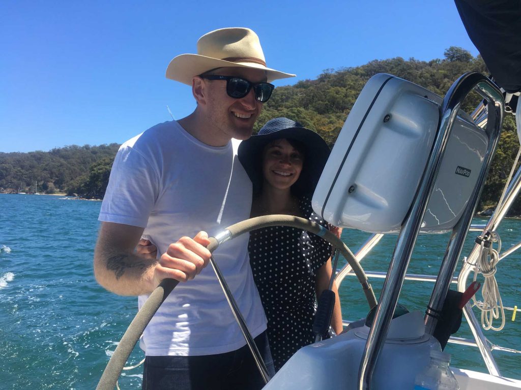 A couple at the wheel of Sha Meduza on Pittwater